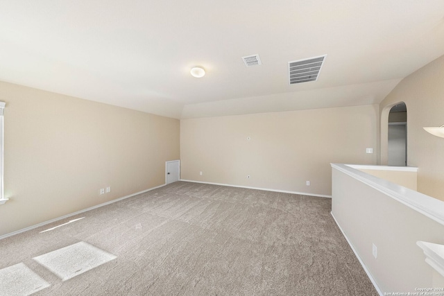 carpeted empty room with lofted ceiling