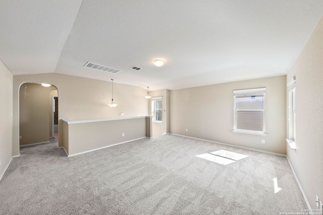 carpeted empty room featuring lofted ceiling and a textured ceiling