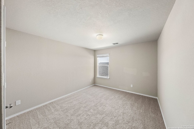 spare room with a textured ceiling and carpet