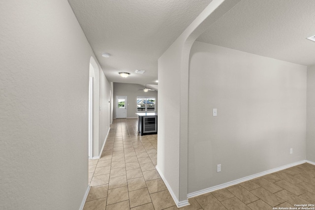 hall featuring a textured ceiling and beverage cooler