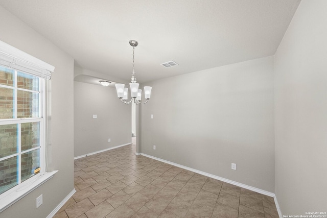 unfurnished room with a notable chandelier