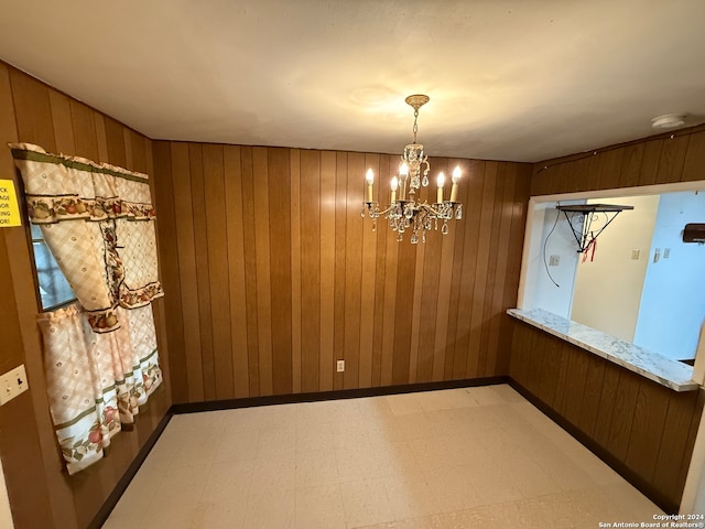 dining room featuring wooden walls and a chandelier