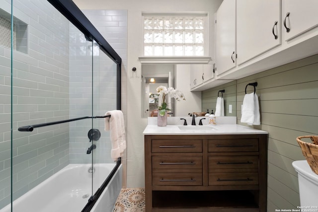 full bathroom featuring toilet, vanity, and shower / bath combination with glass door