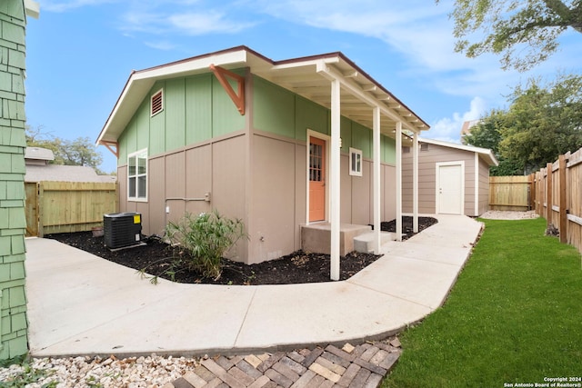 view of property exterior featuring central AC unit, a shed, a yard, and a patio area