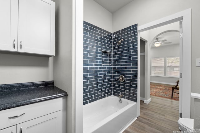 full bathroom featuring vanity, hardwood / wood-style floors, toilet, tiled shower / bath, and ceiling fan