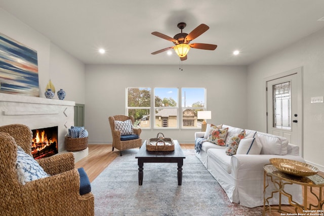 living room featuring light hardwood / wood-style flooring, ceiling fan, and a high end fireplace