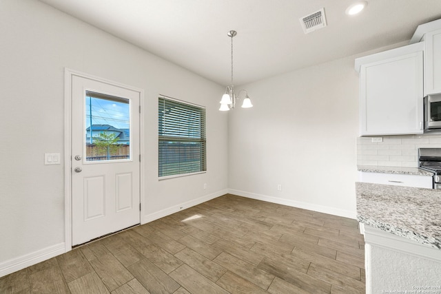 unfurnished dining area with a notable chandelier and light hardwood / wood-style flooring