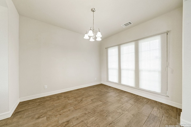 empty room with hardwood / wood-style flooring and a chandelier