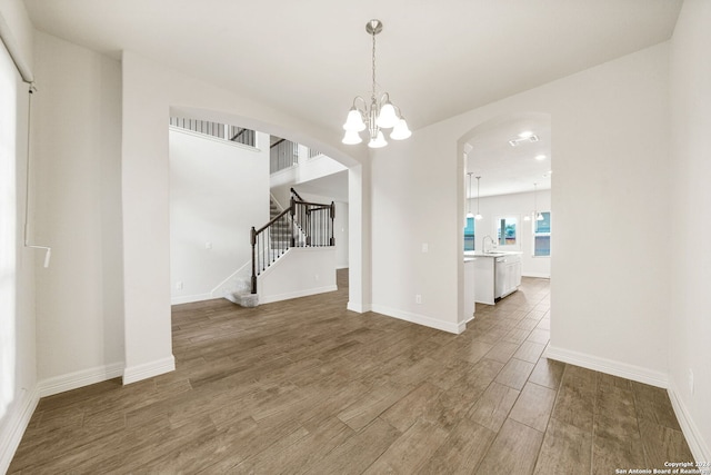 unfurnished dining area with hardwood / wood-style flooring, sink, and a notable chandelier