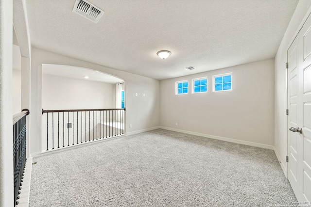 carpeted spare room with a textured ceiling