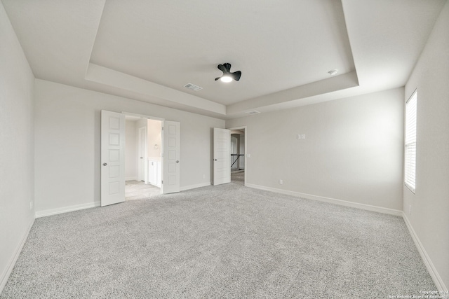 unfurnished bedroom with light carpet and a raised ceiling