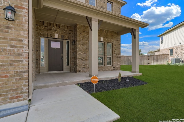 doorway to property with central AC unit, a porch, and a yard