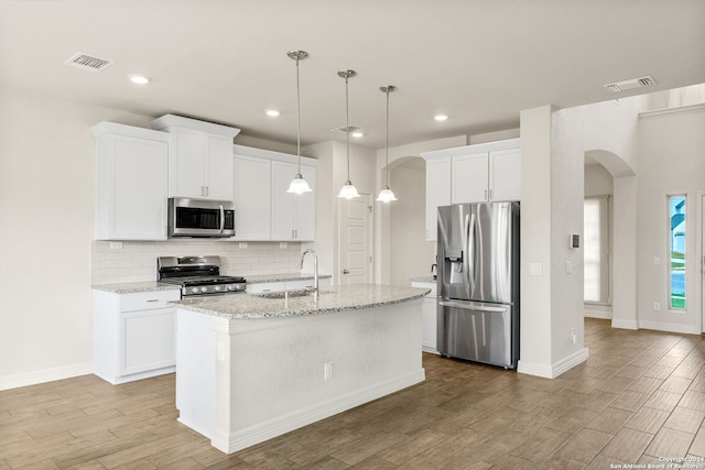 kitchen featuring a kitchen island with sink, stainless steel appliances, white cabinetry, and light hardwood / wood-style floors