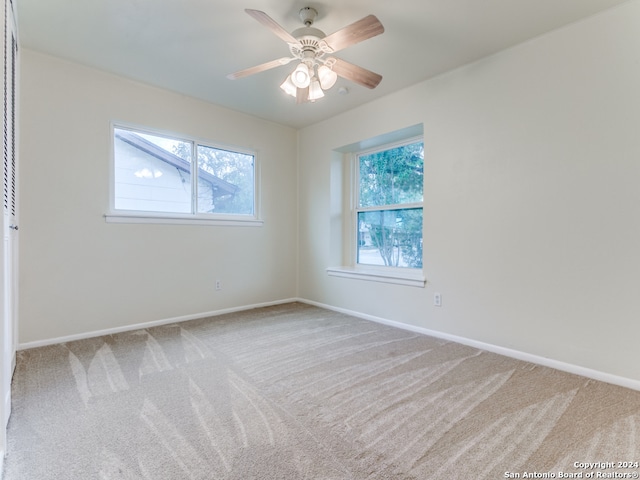 unfurnished room with ceiling fan, light colored carpet, and plenty of natural light