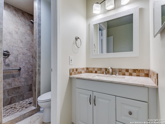 bathroom featuring toilet, vanity, and tiled shower