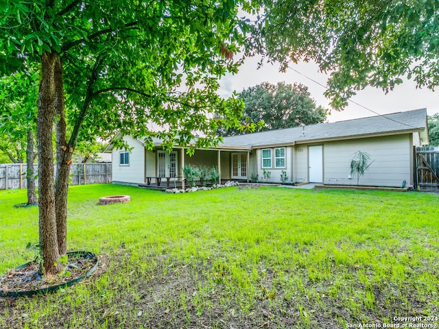 rear view of property featuring a fire pit and a yard