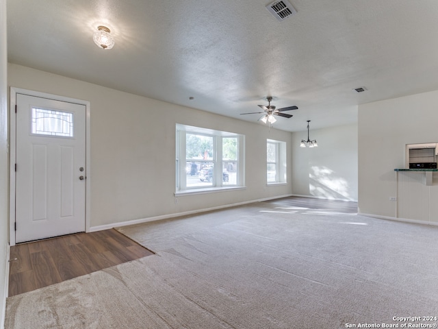 carpeted entryway with a textured ceiling and ceiling fan with notable chandelier