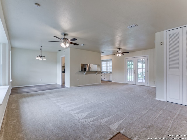 unfurnished living room featuring french doors, ceiling fan with notable chandelier, and carpet