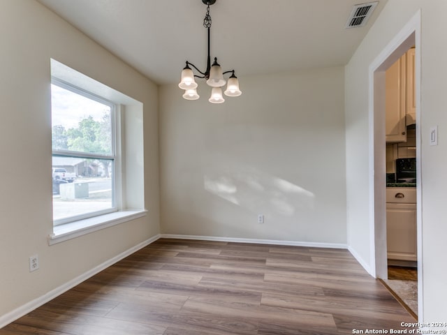 unfurnished dining area with light hardwood / wood-style floors and a chandelier