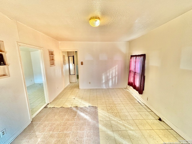 tiled spare room with a textured ceiling