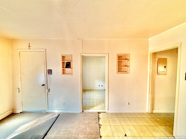 empty room with electric panel and a textured ceiling