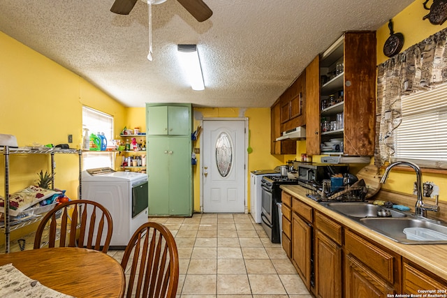 kitchen featuring gas range, a textured ceiling, sink, light tile patterned floors, and washer / clothes dryer