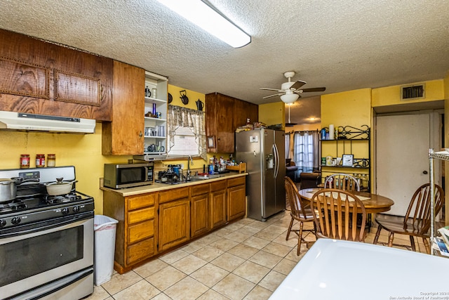 kitchen with a healthy amount of sunlight, a textured ceiling, ceiling fan, light tile patterned flooring, and appliances with stainless steel finishes