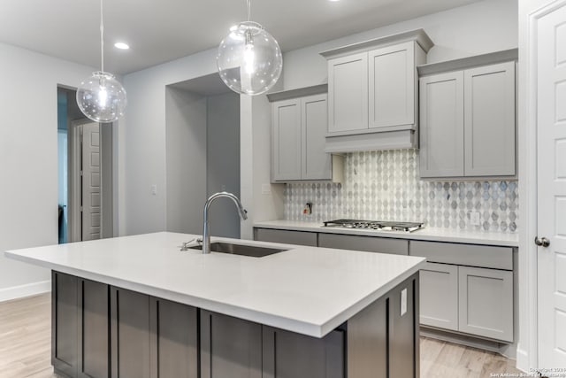 216 Paint Crk, Boerne, TX 78006 - kitchen with a sink, gray cabinets, stainless steel gas cooktop, light wood-style flooring, and decorative backsplash