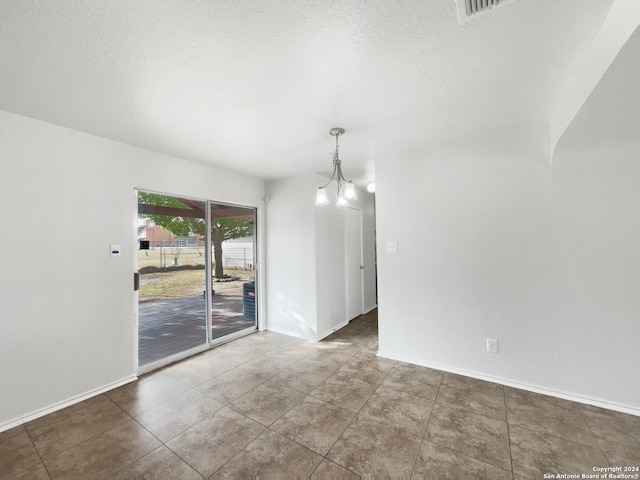 interior space featuring a chandelier, a textured ceiling, and tile patterned flooring