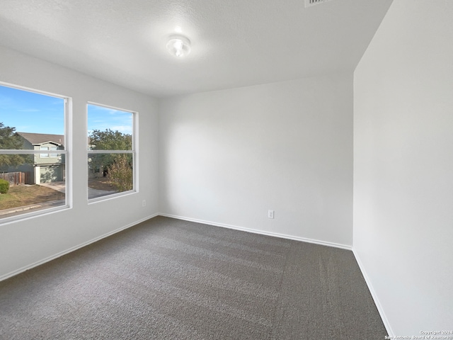 empty room with a textured ceiling and dark carpet