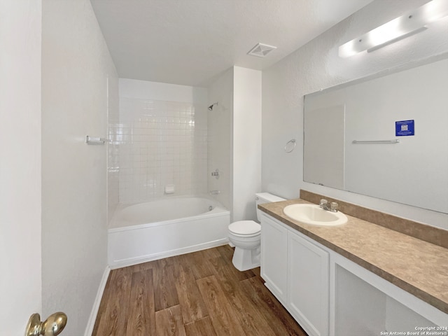 full bathroom featuring hardwood / wood-style floors, vanity, toilet, and tiled shower / bath combo