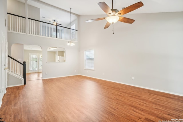 unfurnished living room featuring high vaulted ceiling, wood-type flooring, french doors, and ceiling fan with notable chandelier