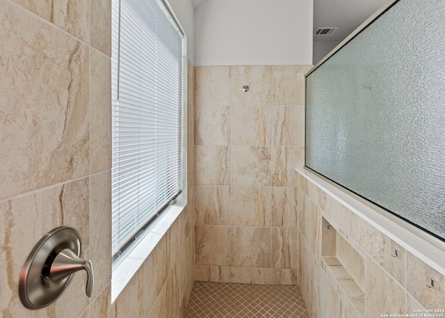 bathroom featuring tile walls, a wealth of natural light, and tiled shower