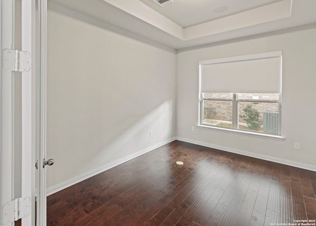 unfurnished room featuring dark wood-type flooring and a raised ceiling