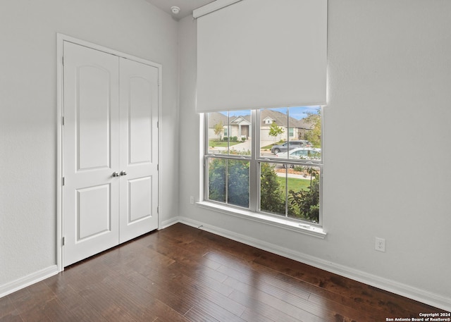 unfurnished bedroom with dark hardwood / wood-style floors and a closet