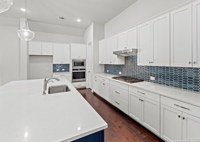 kitchen with stainless steel appliances, dark wood-type flooring, sink, white cabinetry, and decorative light fixtures