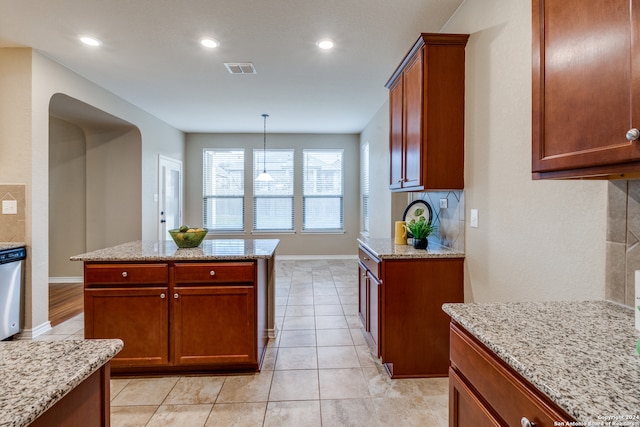 kitchen with light stone counters, a center island, decorative light fixtures, and light tile patterned flooring