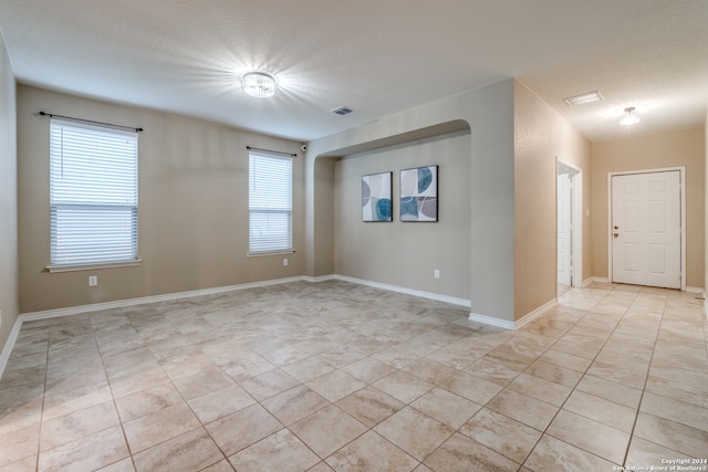 spare room featuring plenty of natural light, light tile patterned floors, and a textured ceiling