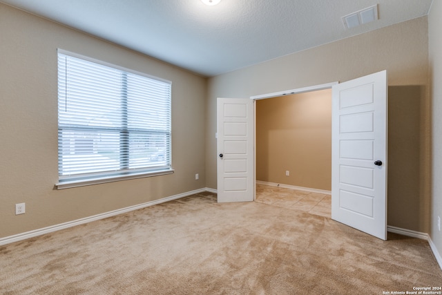 unfurnished bedroom with light colored carpet and a textured ceiling