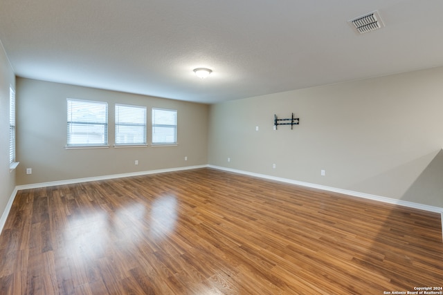 unfurnished room featuring wood-type flooring and a textured ceiling