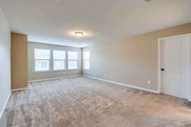 carpeted spare room with a textured ceiling