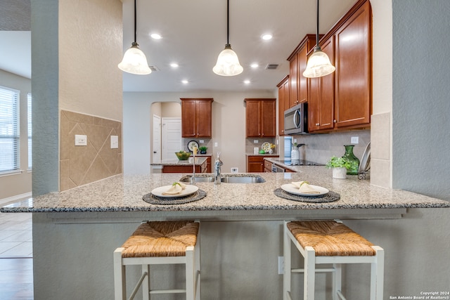 kitchen featuring hanging light fixtures, kitchen peninsula, sink, and a breakfast bar area