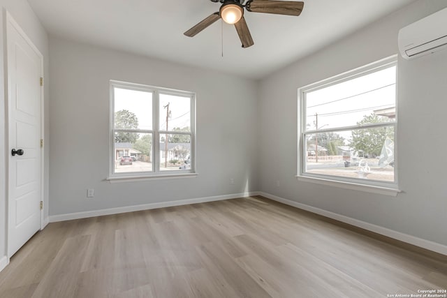 spare room featuring ceiling fan, a wall mounted AC, and light hardwood / wood-style floors