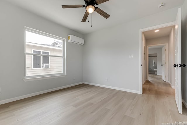 spare room with an AC wall unit, cooling unit, ceiling fan, and light hardwood / wood-style flooring