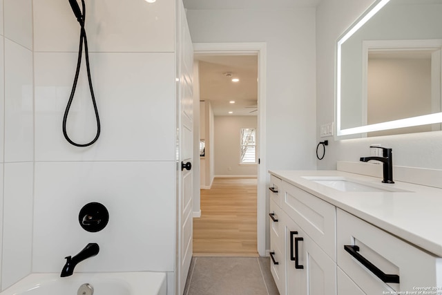 bathroom featuring wood-type flooring, shower / bathtub combination, and vanity