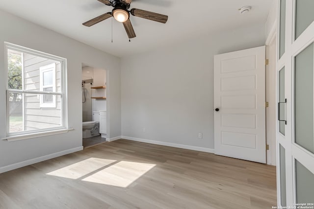 unfurnished bedroom featuring ceiling fan, light hardwood / wood-style flooring, a walk in closet, connected bathroom, and a closet