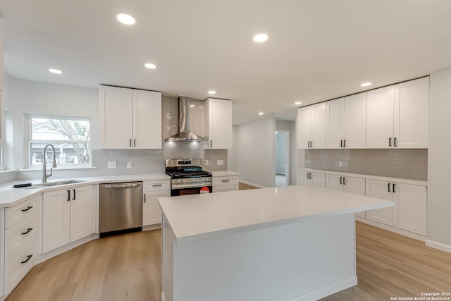 kitchen with white cabinetry, wall chimney range hood, appliances with stainless steel finishes, and sink