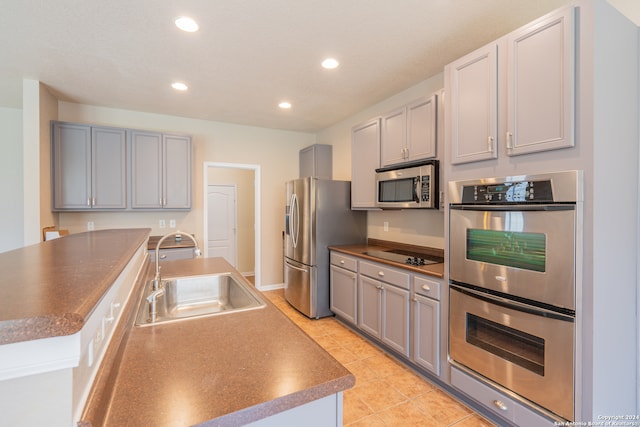 kitchen featuring stainless steel appliances, gray cabinetry, sink, and light tile patterned floors