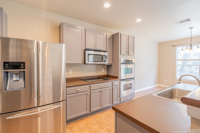 kitchen featuring stainless steel appliances, sink, decorative light fixtures, a notable chandelier, and gray cabinets