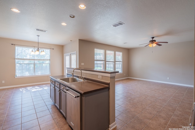 kitchen featuring light tile patterned flooring, hanging light fixtures, sink, dishwasher, and ceiling fan with notable chandelier